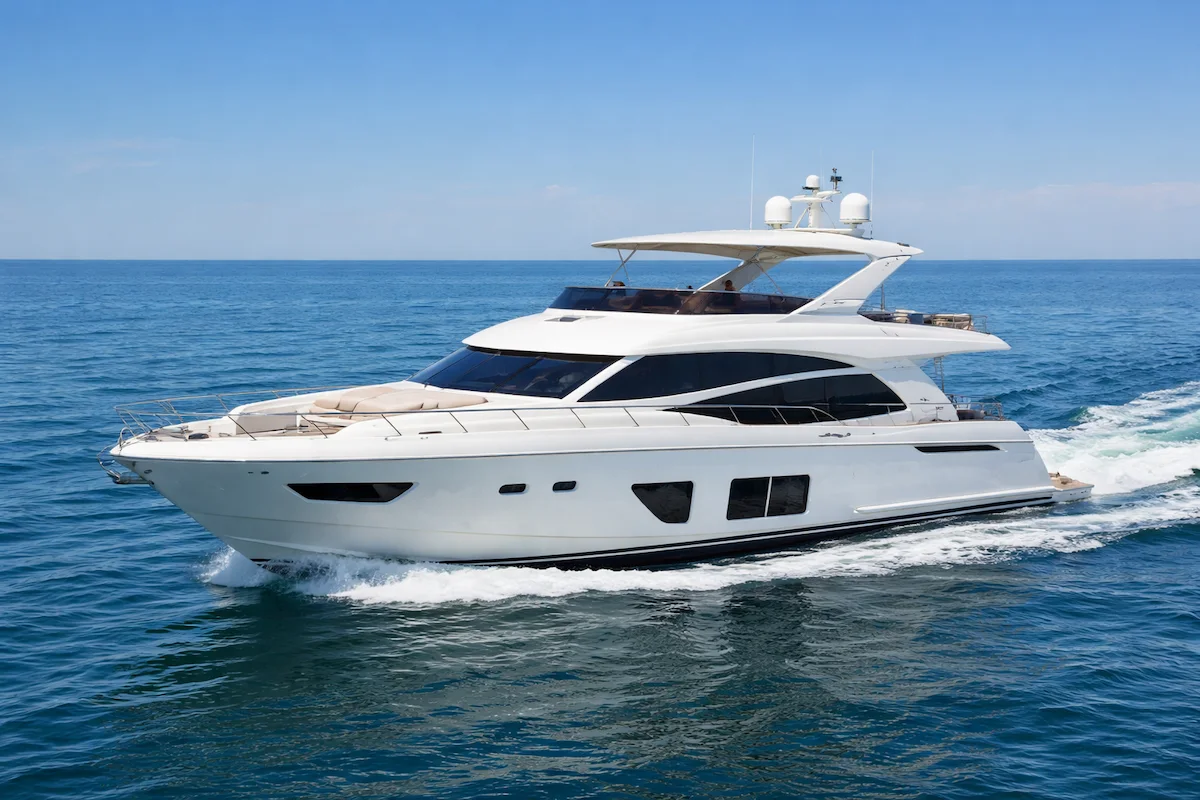 Luxury white yacht sailing on the open ocean under a clear blue sky, used for leisure and recreation.